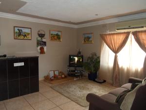 a living room with a couch and a tv at Hardrock Guest House in Francistown