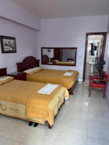 a room with three beds and a red chair at Hotel Tuấn Anh in Vô Hối