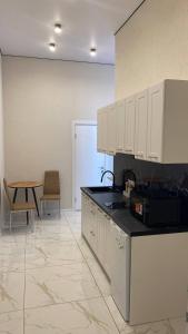 a kitchen with white cabinets and a table and a chair at DiAmel in Petropavlovskaya Borshchagovka +6 photos