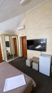 a bedroom with a bed and a flat screen tv at DiAmel in Petropavlovskaya Borshchagovka