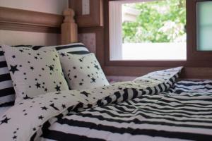 a bed with black and white pillows and a window at Milyang Sweety Pension in Miryang
