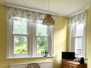 a room with two windows and a desk with a television at Swan Lodge in Swanage