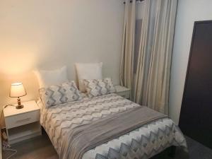 a bedroom with a bed and a night stand with a lamp at Apartment 8, 7373A, Mtedza Rd in Lusaka