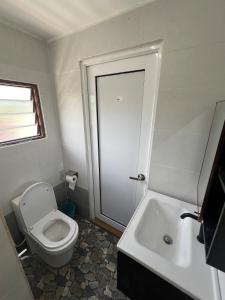 a white bathroom with a toilet and a sink at Wadi Al Hasyer Homestay Daisy in Juasseh