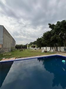 a swimming pool in front of a yard with tables and chairs at Palm resort in Greater Noida