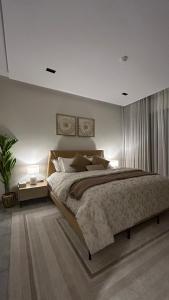 a bedroom with a large bed and a side table at M Residence in Dhahran