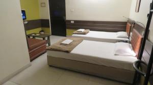 two twin beds in a room with a mirror at The Boulevard Hotel in Jamshedpur
