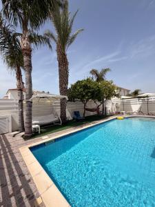 a swimming pool with palm trees next to a house at Villa Andy-350 m from the beach in Larnaca