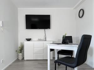 a white desk with a chair and a tv on a wall at Fewo Diemelsee 4 in Heringhausen