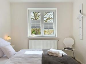 a white bedroom with a bed and a window at Fewo Diemelsee 4 in Heringhausen