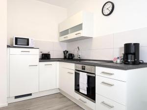 a kitchen with white cabinets and a clock on the wall at Fewo Diemelsee 1 in Heringhausen