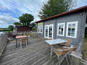 a deck with tables and chairs and a house at Meadow Lakes in St Austell