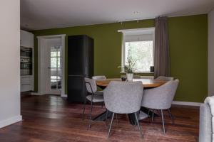a dining room with green walls and a wooden table and chairs at De Bosberg Villa in Appelscha
