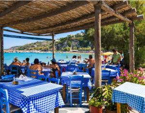 a restaurant with blue and white tables and the beach at Spitaki Almyrida in Almyrida