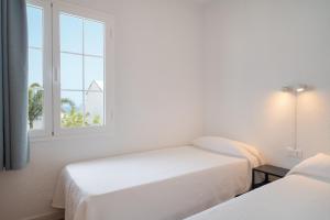 two beds in a room with a window at Apartamentos Celeste in Costa Teguise