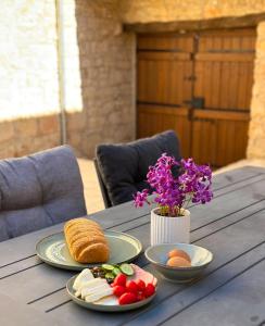 a table with plates of food and a vase of flowers at Eftychia's House in Lofou