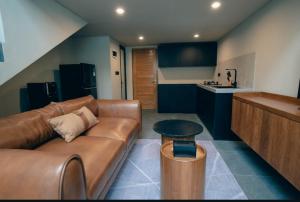 a living room with a brown leather couch and a kitchen at Wolu Designer Loft - Private Pool & Tropical Garden, Canggu in Tumbak Bayuh