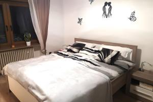 a bed with white sheets and black and white pillows at Zur kleinen Auszeit in Issigau