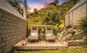 two chairs and a table on a wooden deck with lights at Glamping Kranjc in Kobarid +26 photos