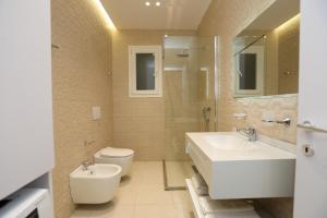 a bathroom with two sinks and a toilet and a mirror at Alrei Apartment in Vlorë +21 photos