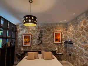 a bedroom with a bed and a stone wall at Rahoni Park & Apartments in Dhërmi
