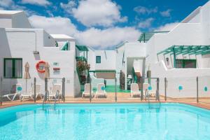 a swimming pool in front of a white building with chairs at Apartamentos Celeste in Costa Teguise +27 photos