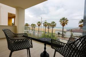 a balcony with a table and chairs and a view of the beach at Seõra Luxury Rooms in Porto Empedocle