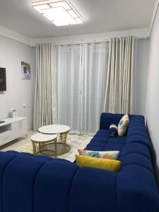 a blue couch in a living room with a table at EM Homes Modern 1-Bedroom Apartment with Pool 15 Minutes from JKIA Airport in Marimbeti +24 photos