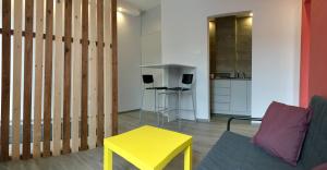 a living room with a yellow table and a kitchen at Emilia - У центрі міста, Приватне паркування в закритому дворі in Mukacheve