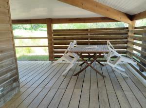 a picnic table and two white chairs on a deck at Appartement 4p Sanguinet-Doum Doum in Sanguinet