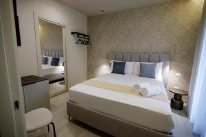 a bedroom with a large white bed and a mirror at Seõra Luxury Rooms in Porto Empedocle