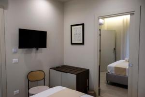 a room with two beds and a television on the wall at Seõra Luxury Rooms in Porto Empedocle