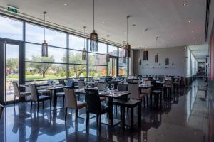 a dining room with tables and chairs and large windows at Vila Gale Lagos in Lagos