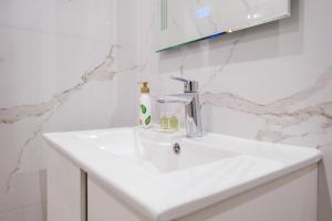 a white bathroom sink with a soap dispenser on it at River View 1-Bedroom Apartment in Plovdiv +23 photos