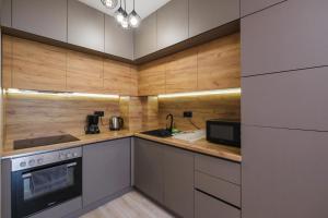 a kitchen with wooden cabinets and a stove top oven at River View 1-Bedroom Apartment in Plovdiv