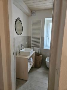 a bathroom with a sink and a mirror and a toilet at La Cereria MARIA in Chiavenna