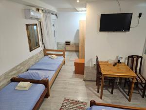 a room with two beds and a table and a tv at Prenociste Simke 2 in Subotica