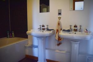 two white sinks in a bathroom with a tub and a sink at Benview House in Staffin