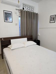 a bedroom with a large white bed and a window at Camellia The Bungalow in Dibrugarh