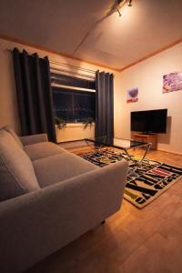a living room with a couch and a flat screen tv at Homestay Hammerfest - Central - Lakeview in Hammerfest