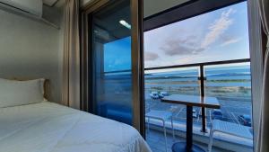 a bedroom with a bed and a table and a large window at Haha pension in Boryeong
