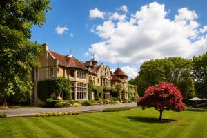 a large house with a tree in the yard at Macdonald Frimley Hall Hotel & Spa in Camberley