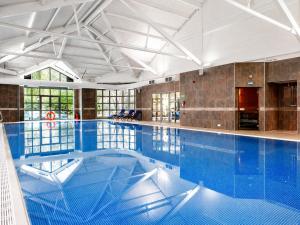 a large swimming pool with blue water at Macdonald Frimley Hall Hotel & Spa in Camberley