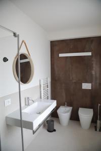 a bathroom with a sink and a toilet and a mirror at TAU Rooms Srl in Tricesimo