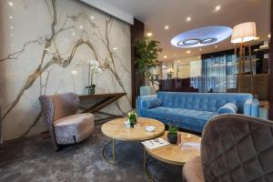 a lobby with a blue couch and chairs and tables at New City Hotel & Restaurant Niš in Niš