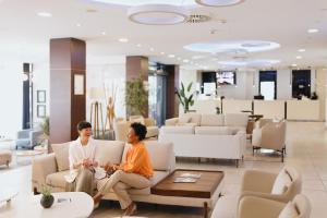 two women sitting on couches in a lobby at New City Hotel & Restaurant Niš in Niš