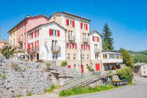 an old building with red windows on a stone wall at Albergo Osteria Leso1815 in Bosco Chiesanuova