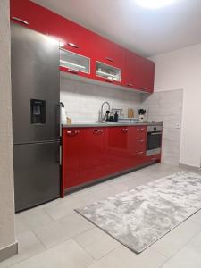 a kitchen with red cabinets and a stainless steel refrigerator at Apartment Alan - Modern Stay in Travnik