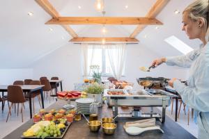 a woman preparing food on a table in a kitchen at Apartamenty Sea Colors - Basen i Sauna! Blisko Plaży - Bardzo Wysoki Standard in Jastrzębia Góra