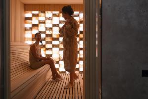 a woman is standing on a wooden floor in a room at New City Hotel & Restaurant Niš in Niš